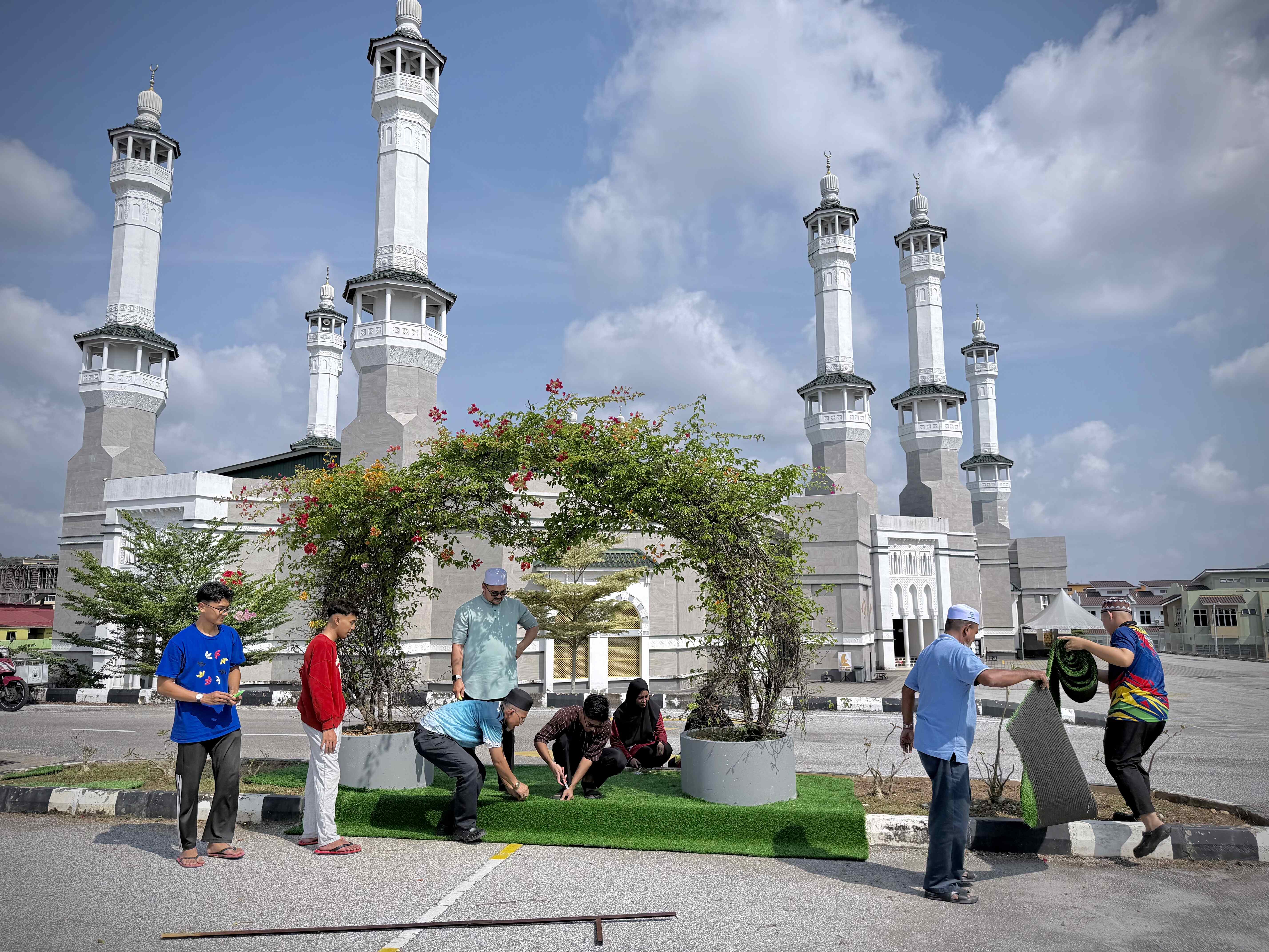 GOTONG-ROYONG PEMASANGAN KARPET RUMPUT TIRUAN DI SEKITAR LANDSKAP MASJID